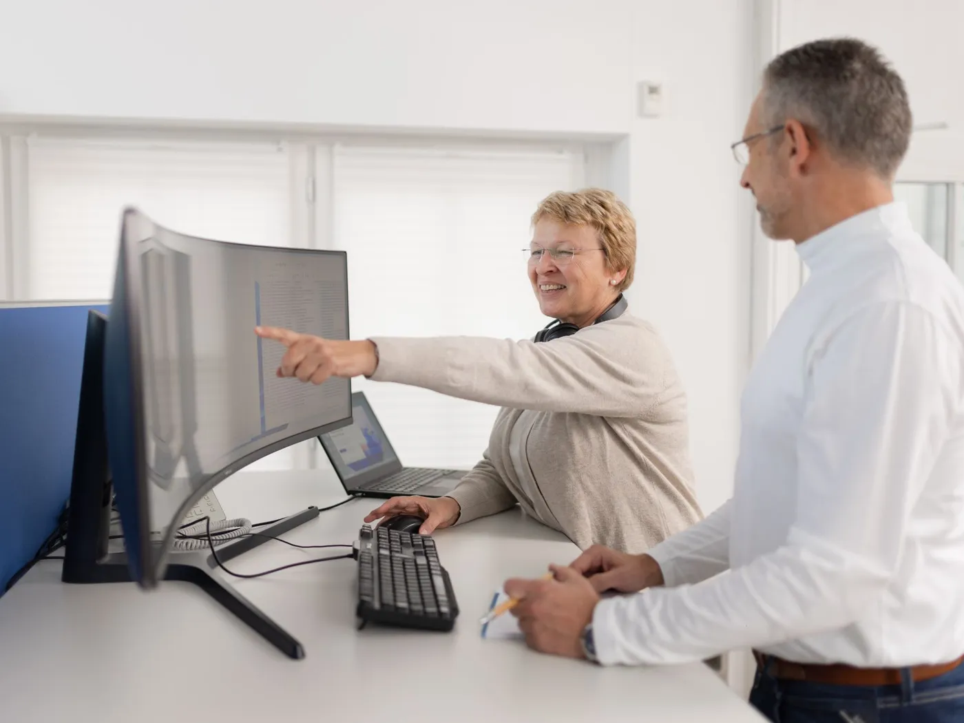 Eine Kollegin und ein Kollege besprechen im Büro eine Auswertung am Bildschirm.