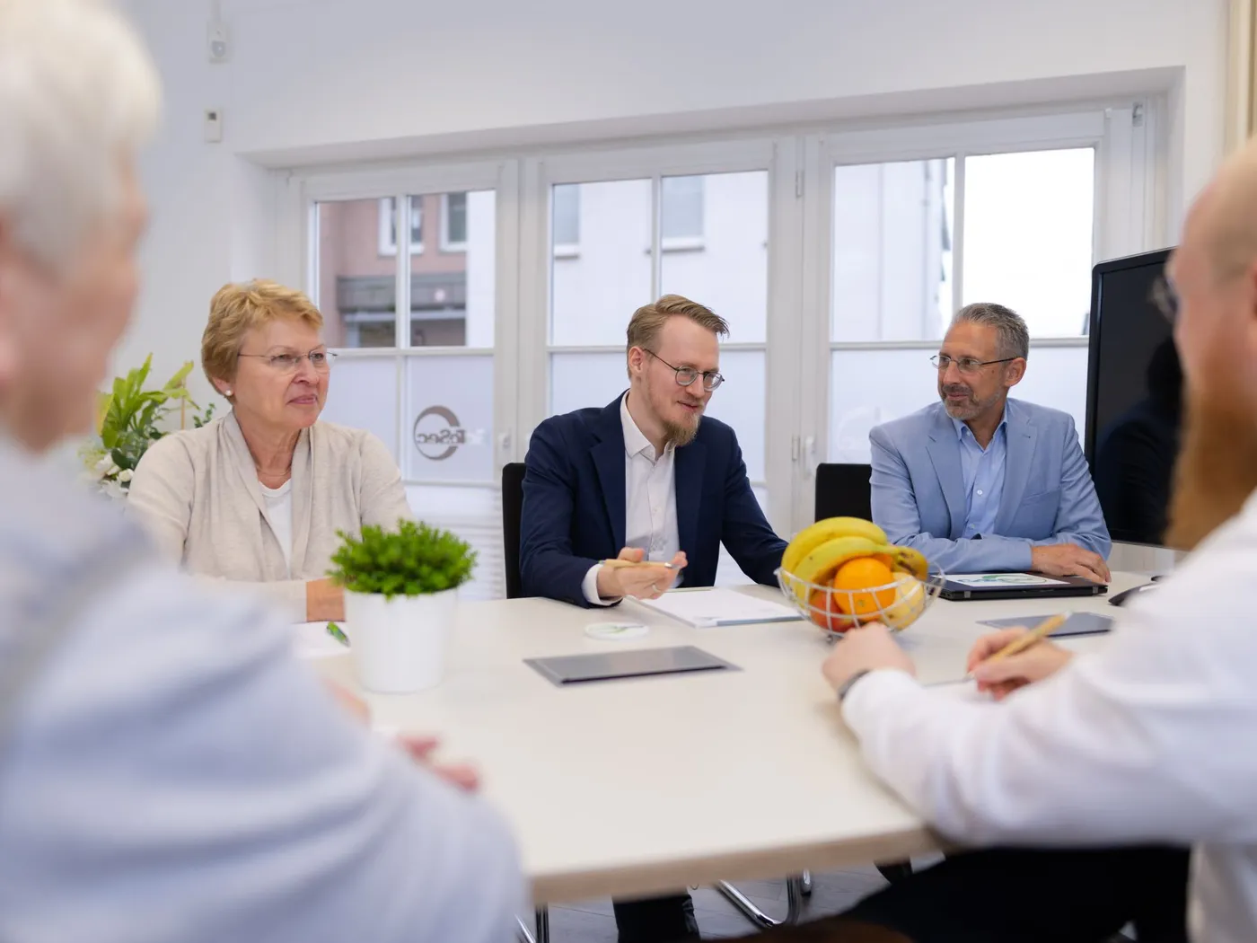 Mehrere Personen sitzen an einem Besprechungstisch im Büro und arbeiten gemeinsam.